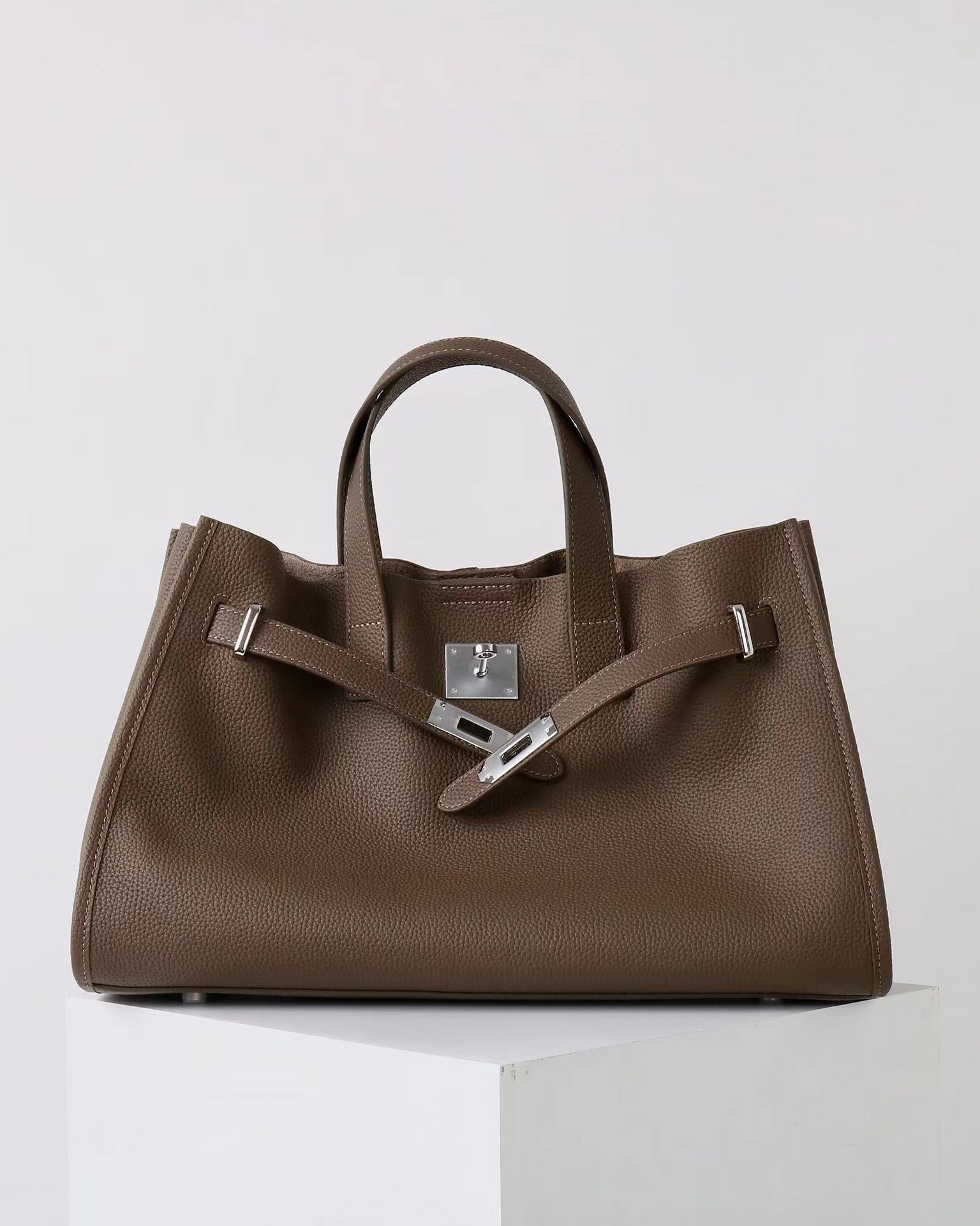 Brown handbag with a silver buckle on a white background
